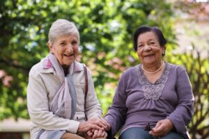two elderly women sitting on bench smiling