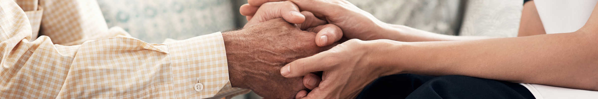Two sets of hands hold each other in a supportive gesture.