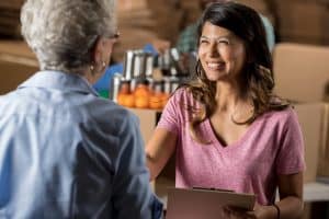 Beautiful food bank organizer greets senior volunteer