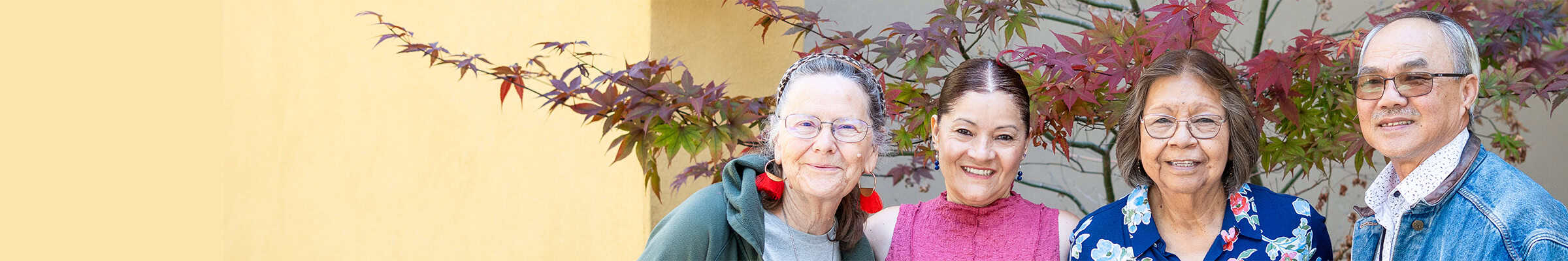Older adults standing in front a tree smiling